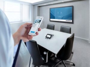 Seamless technology integration for modern meetings: a person using a smartphone to control a presentation on a digital screen in a sleek, well-lit conference room.