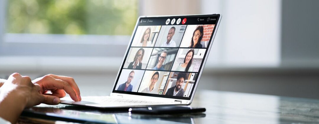 A person participating in a virtual meeting with multiple attendees displayed on a laptop screen.